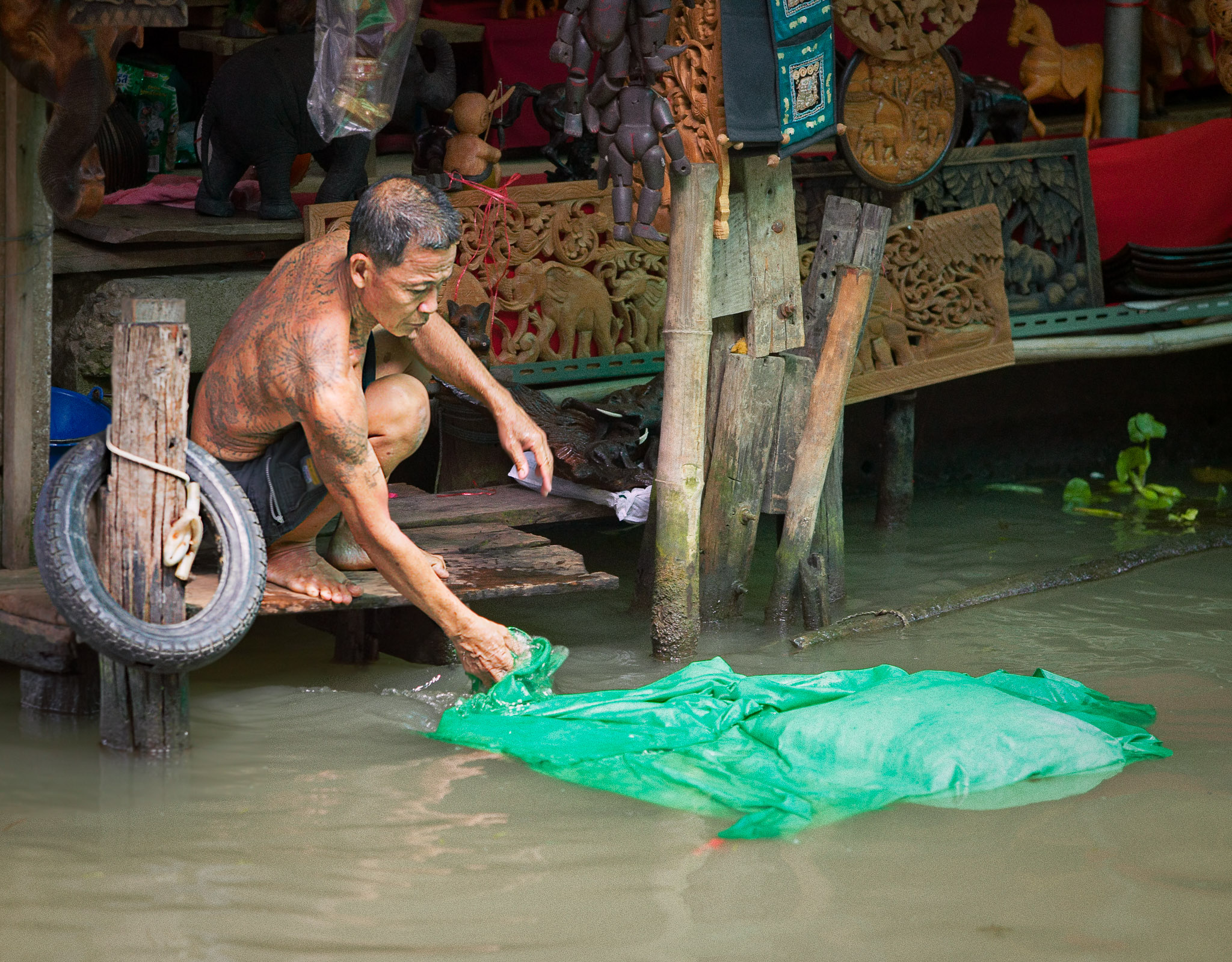 Woodcarver doing laundry, Damnoen Saduak Floating Market, Thailand