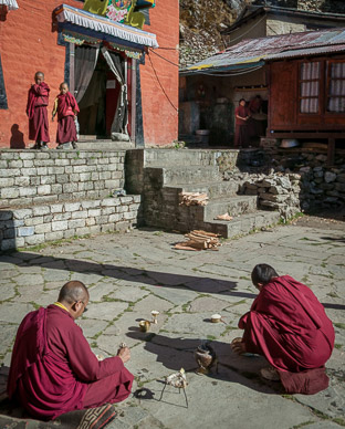 Through open door is very dark cave with a dozen or more chanting monks